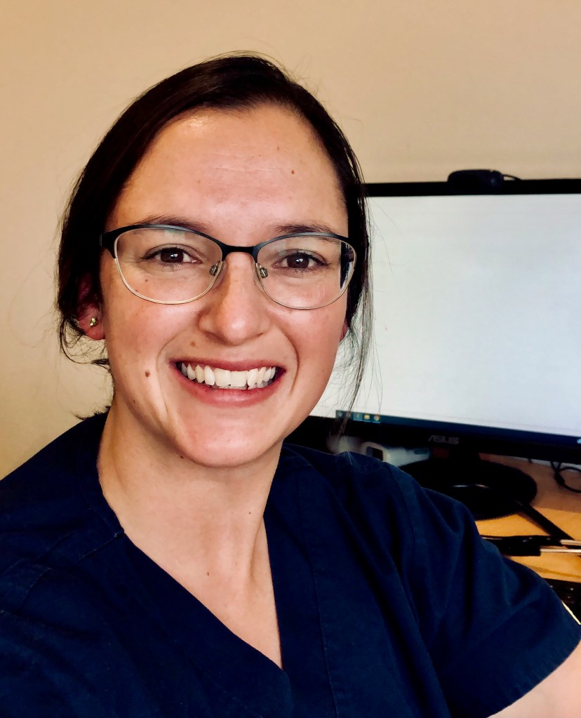 Female GP, Dr Jessica Santos, smiling at the camera in her GP clinic room in Dorrigo Health and Wellbeing.
